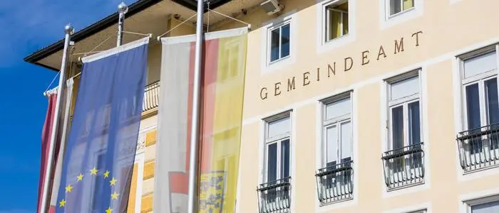 Ein gelbes Gebäude mit der Aufschrift „Gemeindearmt, davor die Kärnten und EU-Fahne