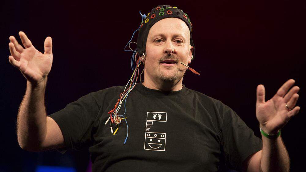 Neurotechniker Reinhold Scherer demonstriert beim Science Slam humorvoll, wie die Gehirnzellen elektrisch stimuliert werden