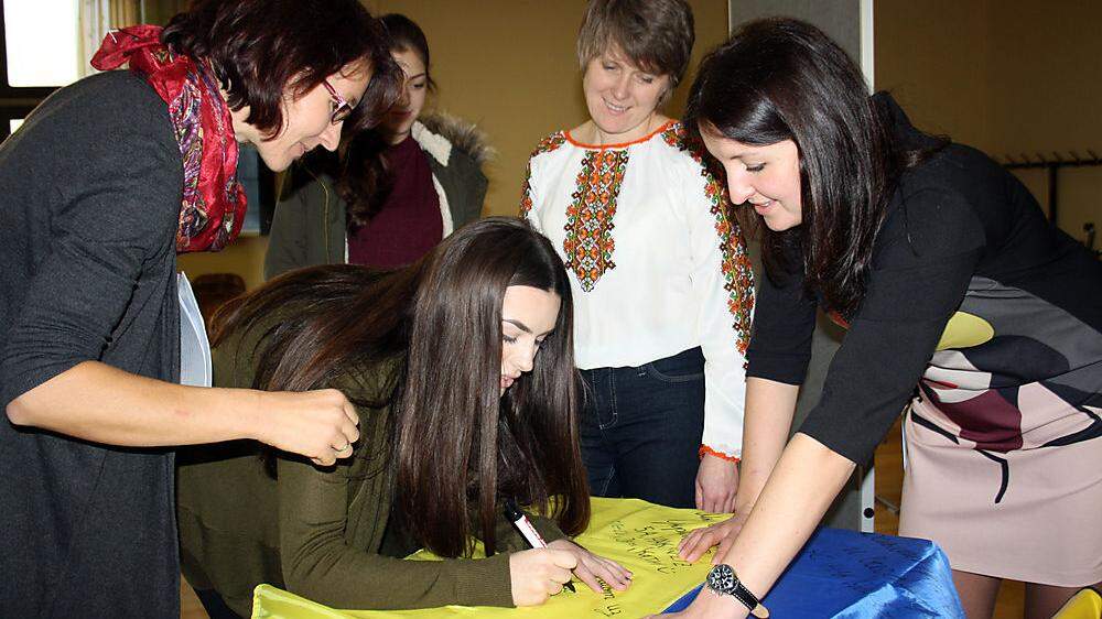 Die Schülerinnen der HAK Weiz schrieben Botschaften auf eine ukrainische Fahne. Larysa Dorosh (2. v. r.) und Tetiana Volosiuk werden sie an ihre Jugendorganisationen übergeben