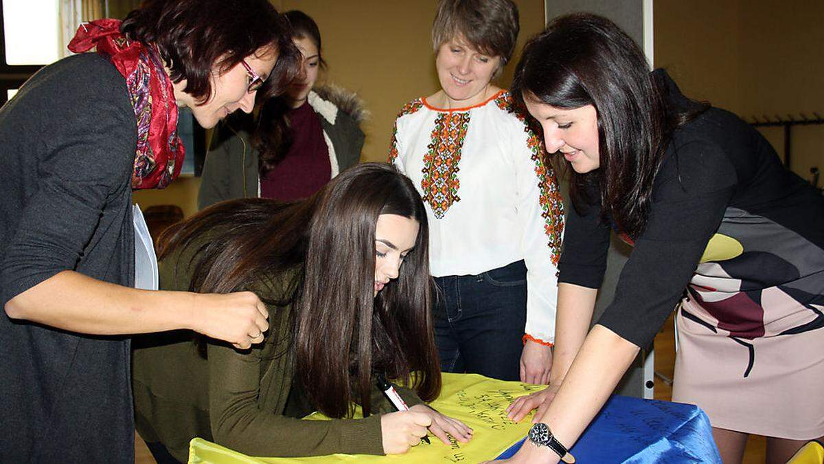 Die Schülerinnen der HAK Weiz schrieben Botschaften auf eine ukrainische Fahne. Larysa Dorosh (2. v. r.) und Tetiana Volosiuk werden sie an ihre Jugendorganisationen übergeben