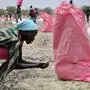 FILE - In this Wednesday, May 2, 2018 file photo, a woman scoops fallen sorghum grain off the ground after an aerial food drop by the World Food Programme (WFP) in the town of Kandak, South Sudan. A record number of people in South Sudan face a critical lack of food according to a new joint report by the government and the United Nations released Friday, June 14, 2019 that says almost seven million people, or more than 60 percent of the population, are at risk. (AP Photo/Sam Mednick, File)