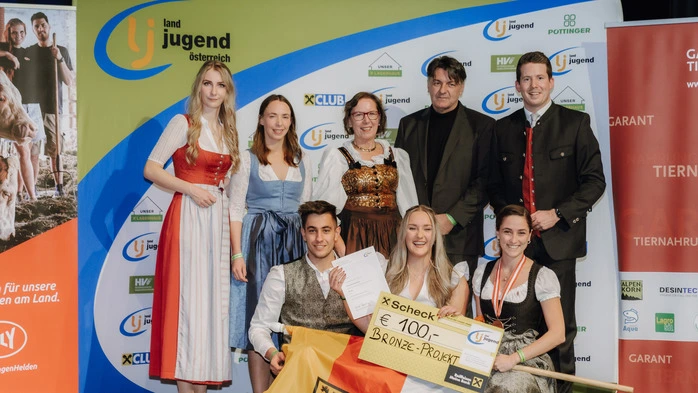 Acht Personen gekleidet in Tracht halten die Kärntner Fahne und freuen sich über die bronzene Auszeichnung | Die Landjugend Gräbern-Prebl konnte sich über Bronze freuen 