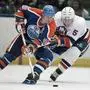 FILE - Edmonton Oilers Wayne Gretzky, left, and New York Islanders Denis Potvin (5) jostle for a loose puck during the first period of an NHL hockey game at the Nassau Coliseum in Uniondale, N.Y., March 26, 1988. (AP Photo/Wa Funches)