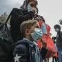 Migrants queue outside Moria camp as they wait to be transferred to the port of Mytilene, on the northeastern Aegean island of Lesbos, Greece, on Sunday, May 3, 2020. Greek authorities are moving 400 migrants, mostly families, to the mainland to help ease overcrowded conditions at the camp. The migrants will arrive in the port of Piraeus on two passenger ships Monday morning. (AP Photo/Panagiotis Balaskas)