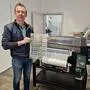 Joachim Kickmeier mit fertigen Motiven vor dem neuen Drucker, der das erste Gerät dieser Art in Österreich war