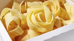 Nahaufnahme von ungekochten, gelben Bandnudeln, die in einer weißen Schachtel liegen | Giftige Rückstände in Semmeln & Spaghetti: Global 2000 warnt vor TFA