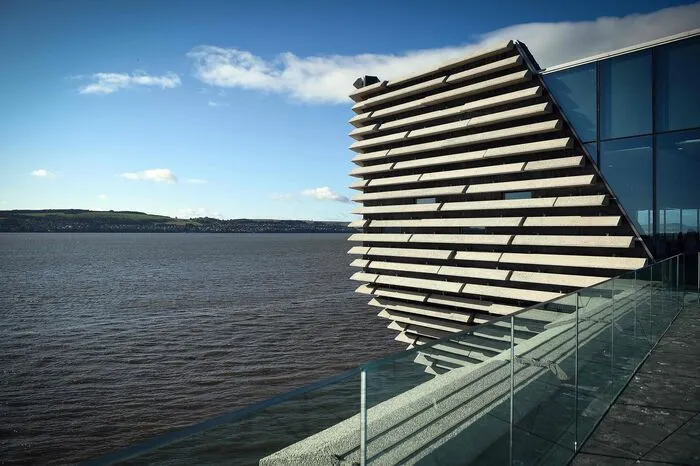 Wie ein riesiger Schiffsrumpf scheint das V&amp;A Dundee aus dem Wasser zu ragen. Grau in grau, wie die Felsklippen der nahen Nordseeküste, fügen sich Tausende von Steinplatten in Wellenform zu einem Ganzen zusammen: Fensterschlitze und Bullaugen bündeln Sonne, Licht und Blicke aufs Wasser.