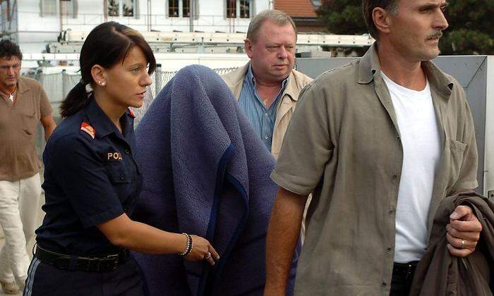 Von einer Decke geschützt, wird Natascha Kampusch von der Polizei in Sicherheit gebracht 