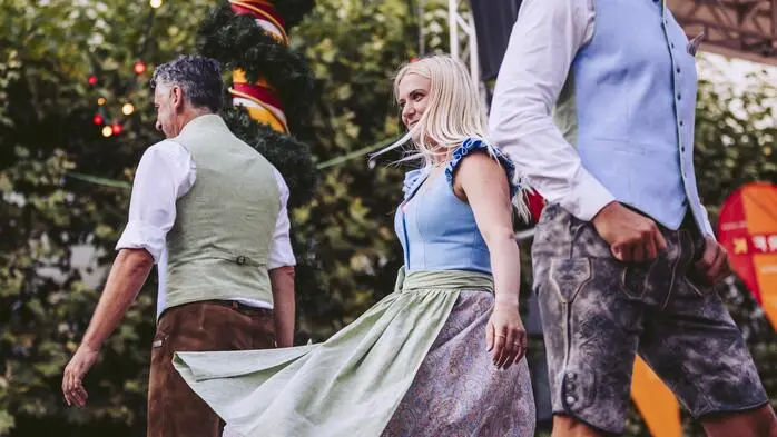 Nahaufnahme einer Trachtenmodenschau. Der Fokus liegt auf einem Dirndl und einer Lederhose