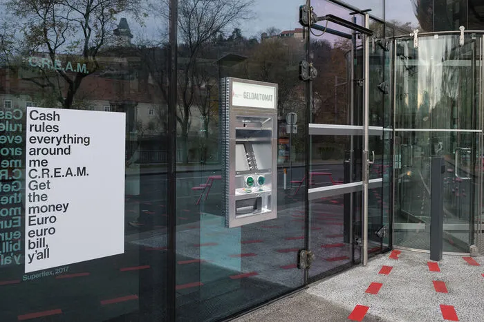 ...stammt von einem Lied der Hip-Hopper Wu-Tang Clan. Ein Textausschnitt ist neben dem Bankomat abgebildet. Er lautet...