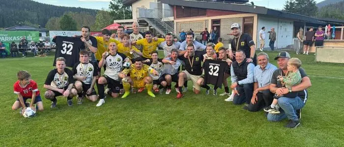 Siegesfoto einer Fußballmannschaft auf einem Fußballrasen mit einem Pokal in der Hand