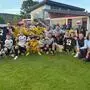 Siegesfoto einer Fußballmannschaft auf einem Fußballrasen mit einem Pokal in der Hand