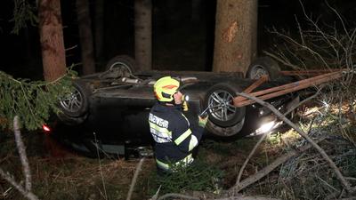 Der auf dem Dach liegende Pkw wurde von der Feuerwehr aus dem Wald gezogen