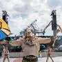 Festivalgast bei Tomorrowland mit ausgestreckten Armen vor der improvisierten Hauptbühne nach dem Großbrand | Das Metallgerippe der abgebrannten Hauptbühne ragt im Hintergrund über die improvisierte Main Stage