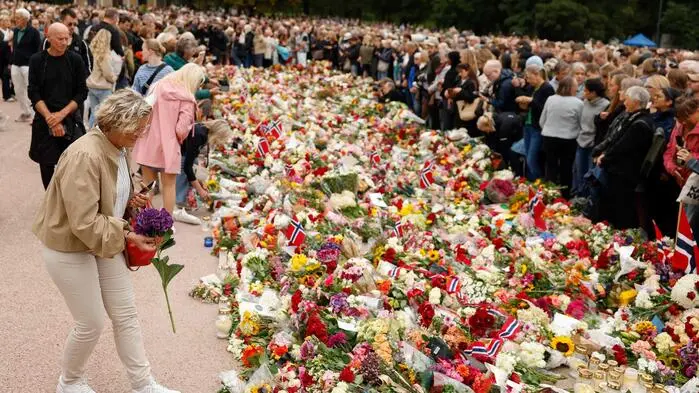 Traunernde legen Blumen vor dem Palast nieder