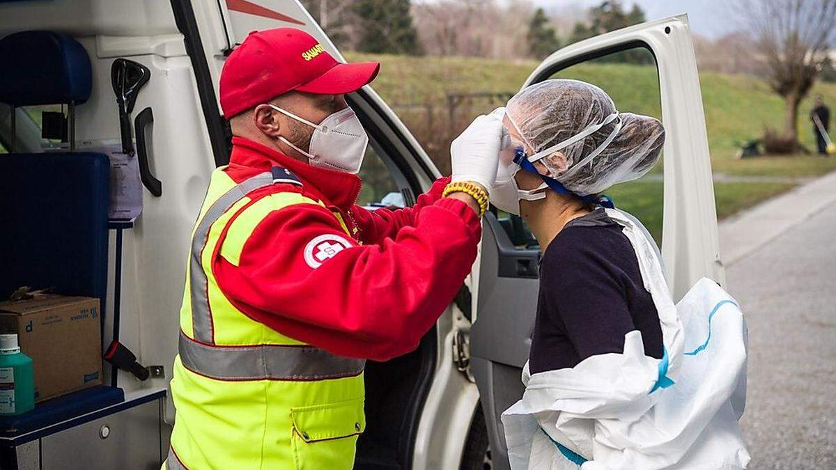 Ein Mitarbeiter des Samariterbundes hilft dem Visitenarzt beim Anlegen der Schutzkleidung