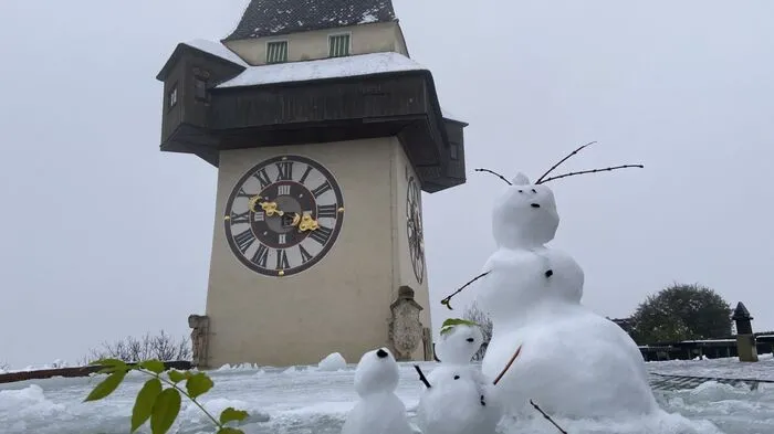Ob eine kleine Schneefamilie vor dem Uhrturm ...