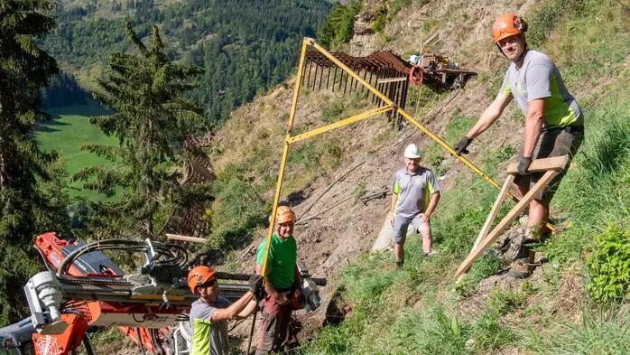 Vier Arbeiter im steilen Gelände