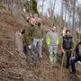 Fünf Männer stehen in einem fast vollständig abgeholzten Wald