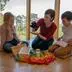 Eine Rainbows-Gruppenleiterin bei der Trauerarbeit mit Kindern, zeigt einen Sarg, Grabkerze und eine Handpuppe