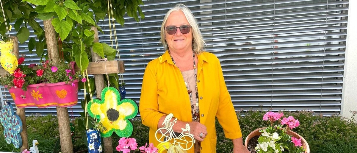 Eine ältere Dame steht inmitten von Blumen 