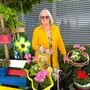 Eine ältere Dame steht inmitten von Blumen 