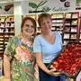 Zwei Frauen in einem Gourmetgeschäft, eine Frau hält einen Erdbeerkuchen in der Hand