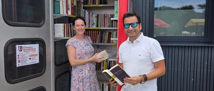 Ein Mann und eine Frau stehen vor einer Telefonzelle voller Bücher