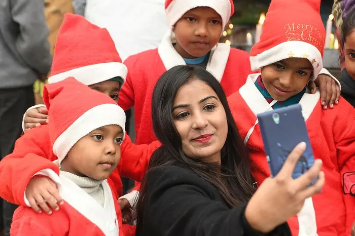 Indische Kinder verkleidet als Weihnachtsmänner feiern die Geburt Jesu.