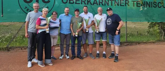 Acht Menschen sind auf einem Foto und lachen auf einem Tennisplatz in die Kamera
