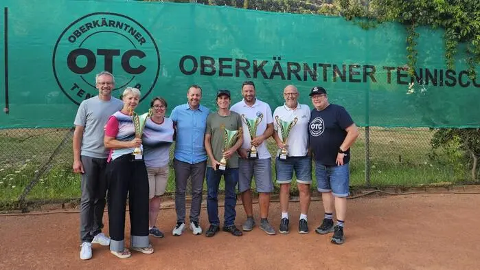 Acht Menschen sind auf einem Foto und lachen auf einem Tennisplatz in die Kamera