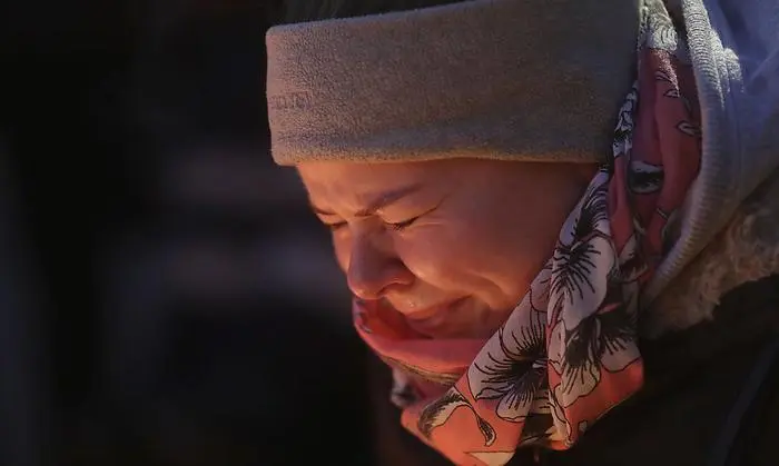 A woman is illuminated by candles as she cries in Berlin, Germany, Tuesday, Dec. 20, 2016, the day after a truck ran into a crowded Christmas market nearby and killed several people. (AP Photo/Markus Schreiber)