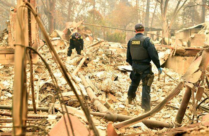 Polizisten suchen die völlig zerstörten Häuser penibel nach Leichen ab