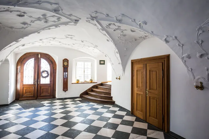 Die Eingangshalle ist eine Kärntner Querlaube mit historisiernden Rankenstukkaturen.