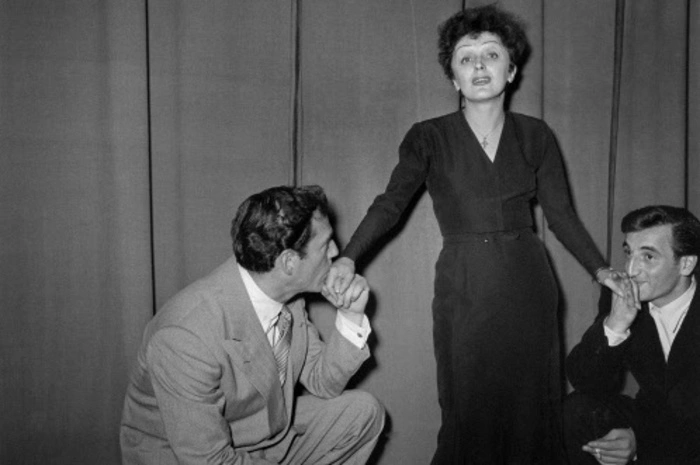Hier gehen Charles Aznavour (rechts) und Eddie Constantine vor Edith Piaf in die Knie.  Die berühmte Chansonniere war entscheidend für seine Karriere. 1946 wurde sie auf ihn aufmerksam und nahm ihn mit auf Tournee durch Frankreich und in die USA.