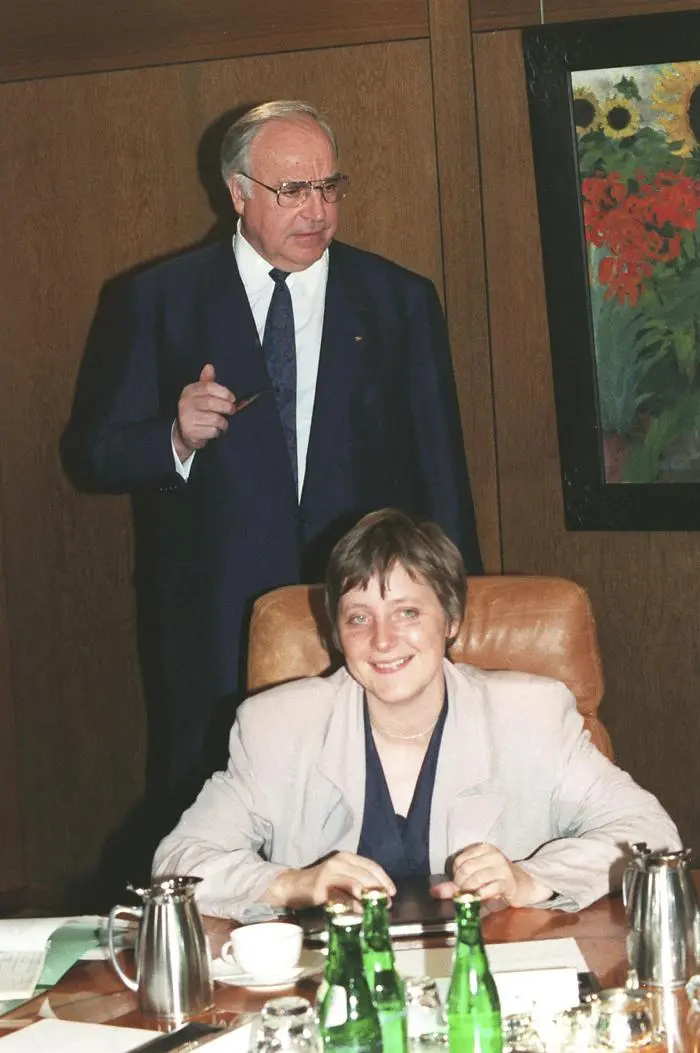 FILE - In this Tuesday, April 30, 1991 file photo, former German Chancellor Helmut Kohl stands behind former Women and Youth Minister and current Chancellor Angela Merkel prior to a cabinet meeting at the chancellery in Bonn, Germany. Twenty years after the unification of East and West Germany, old habits still die hard with even Chancellor Merkel confessing she still can't shed some of her East German tendencies. Merkel, who grew up in communist East Germany, still washes her laundry with East German 'fit' detergent, prepares East Germans' favorite Soljanka soup, an often eclectic mix of ingredients like sausage, cabbage and sour cream in a pickle juice broth for supper and can't fight a predilection to hoard food and other goods. (Foto:Fritz Reiss, File/AP/dapd)
