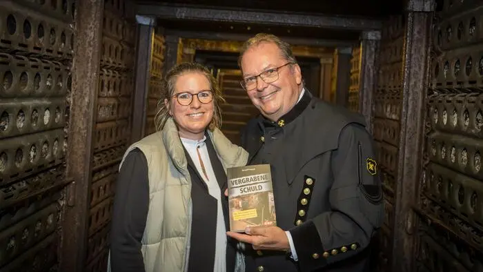 Ein Mann mit einem Buch neben einer Frau im Stollen eines Bergwerks