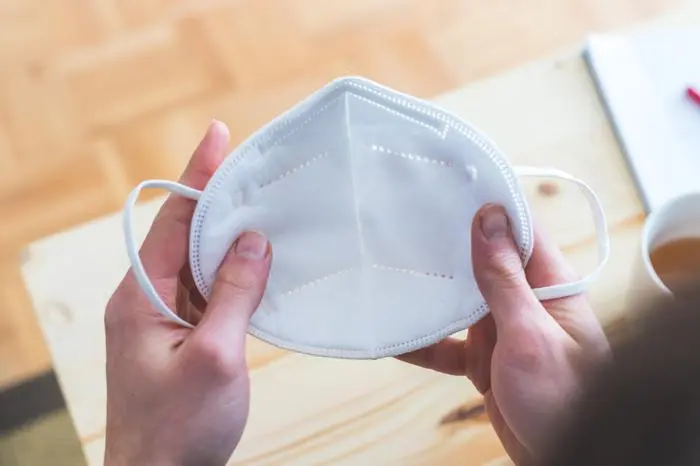 Young man in pulling on ffp2 anti corona mask