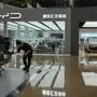 A worker wipes a Rising F7 car model at a floor section selling various Chinese-made electric car brands inside a shopping mall in Beijing, Tuesday, April 4, 2023. Furious at U.S. efforts that cut off access to technology to make advanced computer chips, China's leaders appear to be struggling to figure out how to retaliate without hurting their own ambitions in telecoms, artificial intelligence and other industries. (AP Photo/Andy Wong)