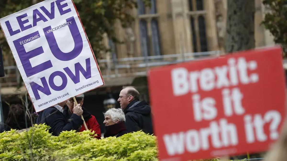 Pro and anti Brexit protesters hold placards as they vie for media attention near Parliament in London, Friday, Nov. 16, 2018.  Britain's Prime Minister May still faces the threat of a no-confidence vote, after several Conservative Party lawmakers said they had written letters asking for one. (AP Photo/Alastair Grant)