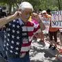A member of the National Rifle Association plugs his ears with his fingers as he walks past protesters during the NRA's annual meeting at the George R. Brown Convention Center in Houston, Friday, May 27, 2022. (AP Photo/Jae C. Hong)
