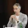 Kurt Hohensinner spricht in ein Mikrofon, die andere Hand gestikuliert. Er trägt einen hellgrauen Blazer mit weißem T-Shirt darunter, die grauen Haare im modernen Kurzhaarschnitt, eine dezente Brille