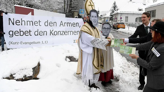 Begrüßung durch die Regierungskritiker von Attac: "Nehmet den Armen, gebet den Konzernen - Kurz-Evangelium 1,1." Mit Maske und in Bischofs-Ornat haben Aktivisten riesige Geldscheine an Konzerne verteilt.