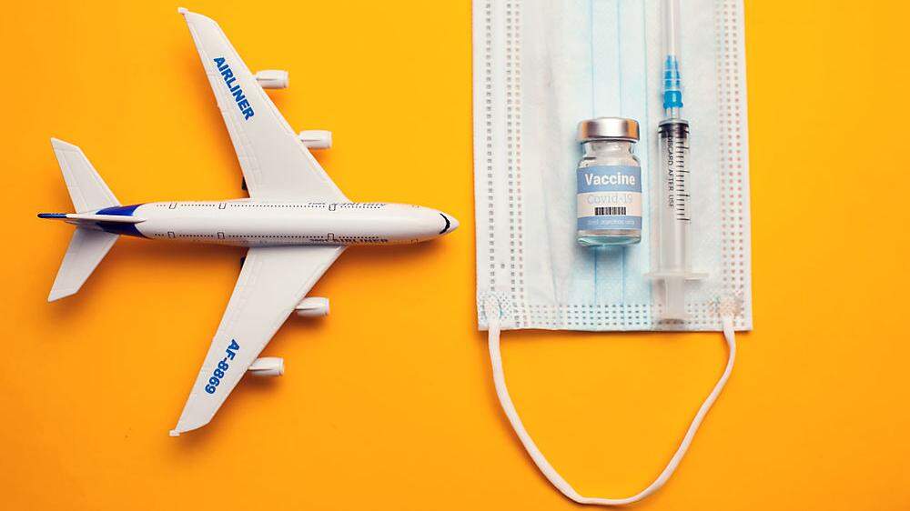Travel during covid-19 pandemic. Airplane model, protection medical mask, vaccine and syringe on yellow background.