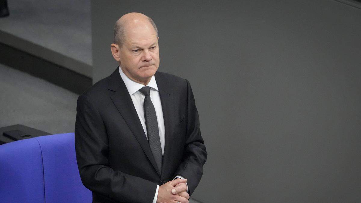 Bundeskanzler Olaf Scholz steht in schwarzem Anzug auf seinem Platz im Bundestag. Die Miene ist angespannt. | Olaf Scholz bei der Debatte zum „Schutz jüdischen Lebens“ im Bundestag