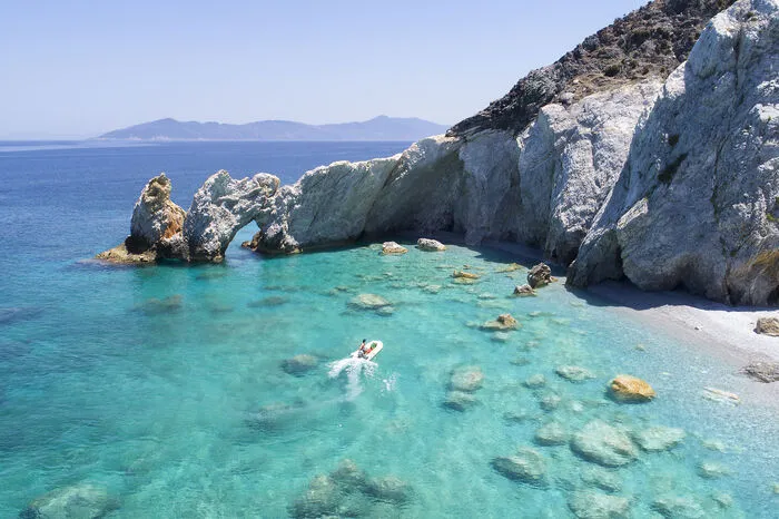 Strand Lalaria - Griechenland. Weißer Kiesstrand, türkisfarbenes Meer und malerische Kreidefelsen - willkommen auf Skiathos! Die Ägäis-Insel bietet viel für Bootsurlauber: Fährt man die Küste entlang bekommt man einen schönen Ausblick auf die abwechselnd mit Kies oder Sand gesäumten Buchten. Ewige Jugend erhält außerdem angeblich der, der am Strand Lalaria durch das Felsentor schwimmt. Sehenswert sind zudem die zahlreichen Meereshöhlen, die bei richtigem Sonnenstand in verschiedenen Blautönen schimmern.