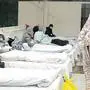This photo taken on February 5, 2020 shows a patient (R) covered with a bed sheet at an exhibition centre converted into a hospital as it starts to accept patients displaying mild symptoms of the novel coronavirus in Wuhan in China's central Hubei province. - China scrambled to find bed space for thousands of newly infected patients on February 6, as the toll from a deadly new virus jumped again with more than 28,000 people known infected nationwide and 563 deaths. (Photo by STR / AFP) / China OUT