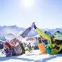 two female friends with ski and snowboard equipment having fun and high five with snow in the air.