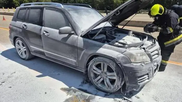 Man sieht einen Feuerwehrmann beim mit Schaum eingedeckten Auto