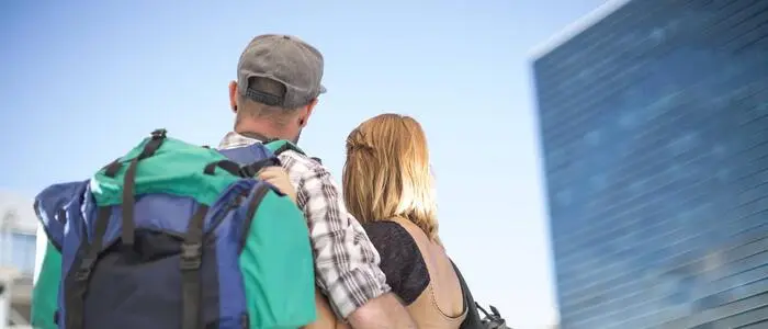 Mann und Frau mit Rucksäcken vor einem hohen Gebäude